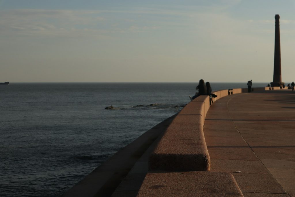 a person sitting on a wall looking out at the ocean